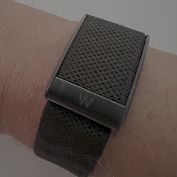 WHOOP 5.0 band worn on the wrist, dark textured fabric strap